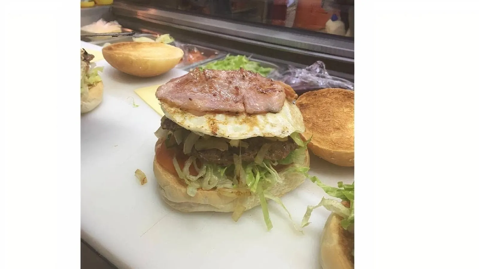 Classic Aussie burger with bacon, egg, lettuce and tomato on prep counter