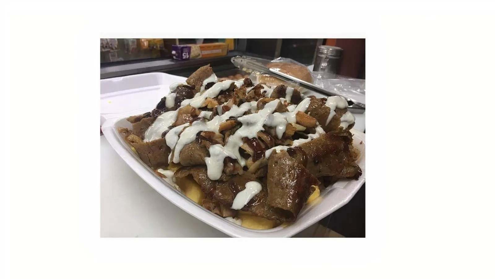 Lamb doner kebab on chips with garlic and BBQ sauce in styrofoam container